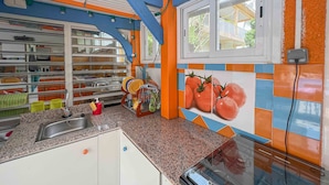 Cozinha com bancada de granito, pia de aço inoxidável e janela com vista para o exterior.