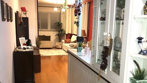 A hallway with a patterned rug, a dark wooden cabinet, and a white railing with glass doors. - Apartment with heating and heated pool near the city center! (RS)