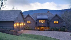 Une grande maison à deux étages, dotée d’un porche avant couvert et d’une allée menant à l’entrée.
