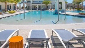 A swimming pool with lounge chairs and palm trees.