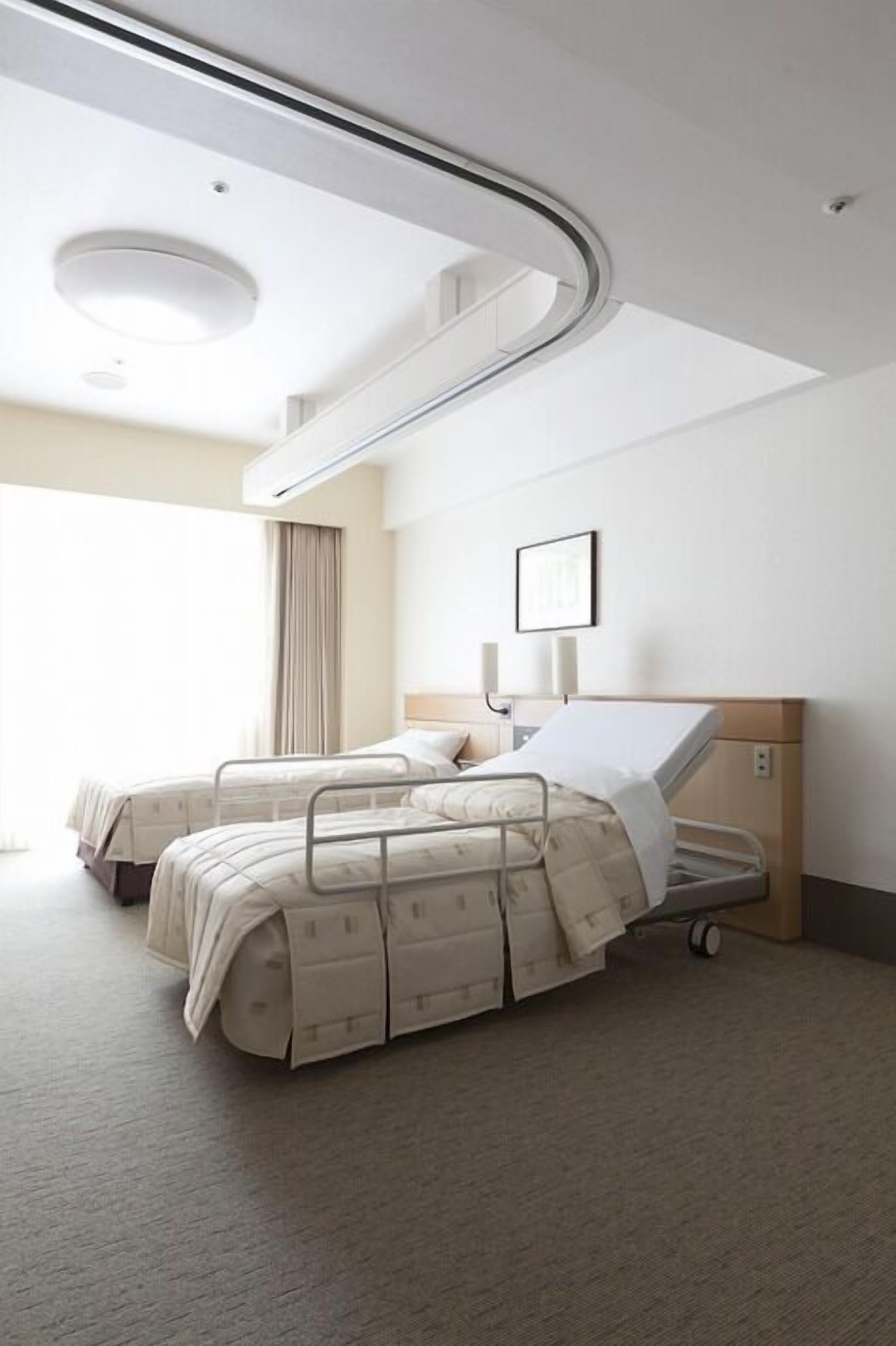 A modern hotel room with two beds, a ceiling light, a bedside table, and a window with curtains.