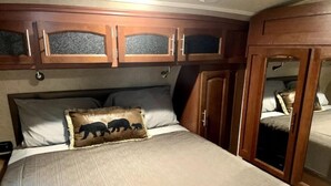 A bedroom with a bed, wooden headboard, and a wardrobe with a mirror. - A Country Escape (Ayden)