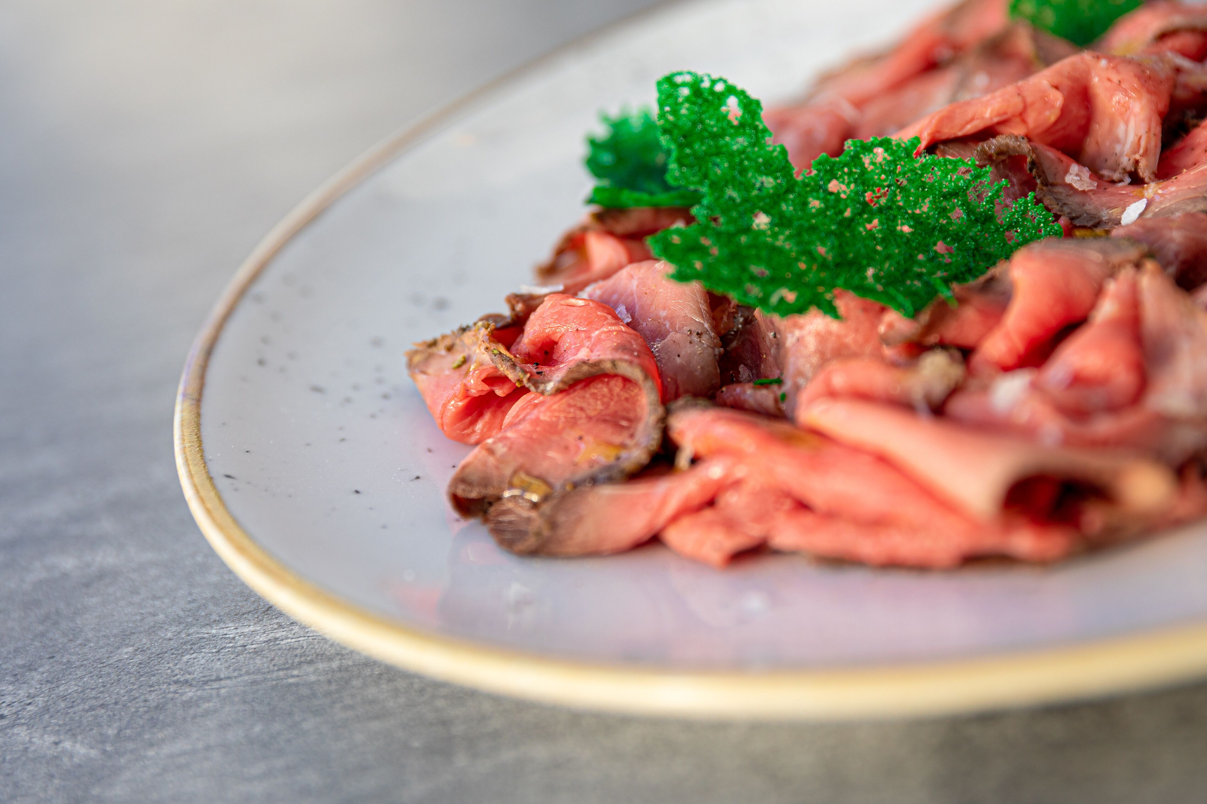 Un plato de carne en rodajas adornado con perejil.