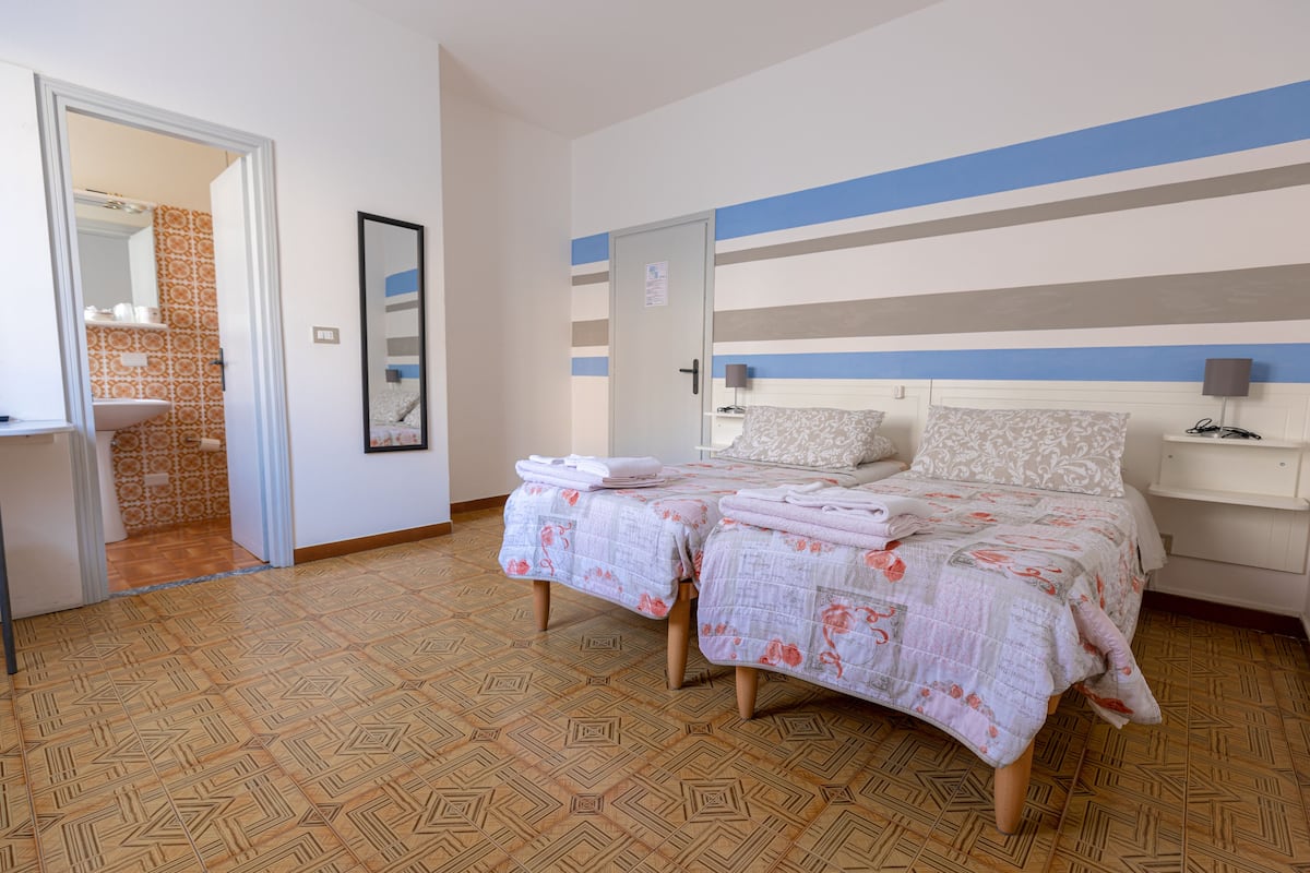 A bedroom with a bed, bedside tables, a mirror, and a door.