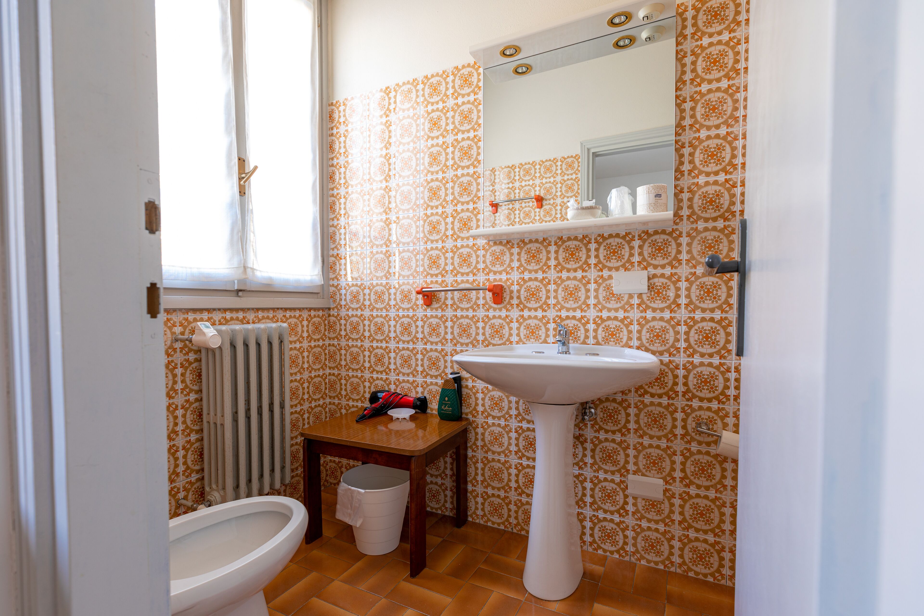 A bathroom with a toilet, sink, and a small table with toiletries.