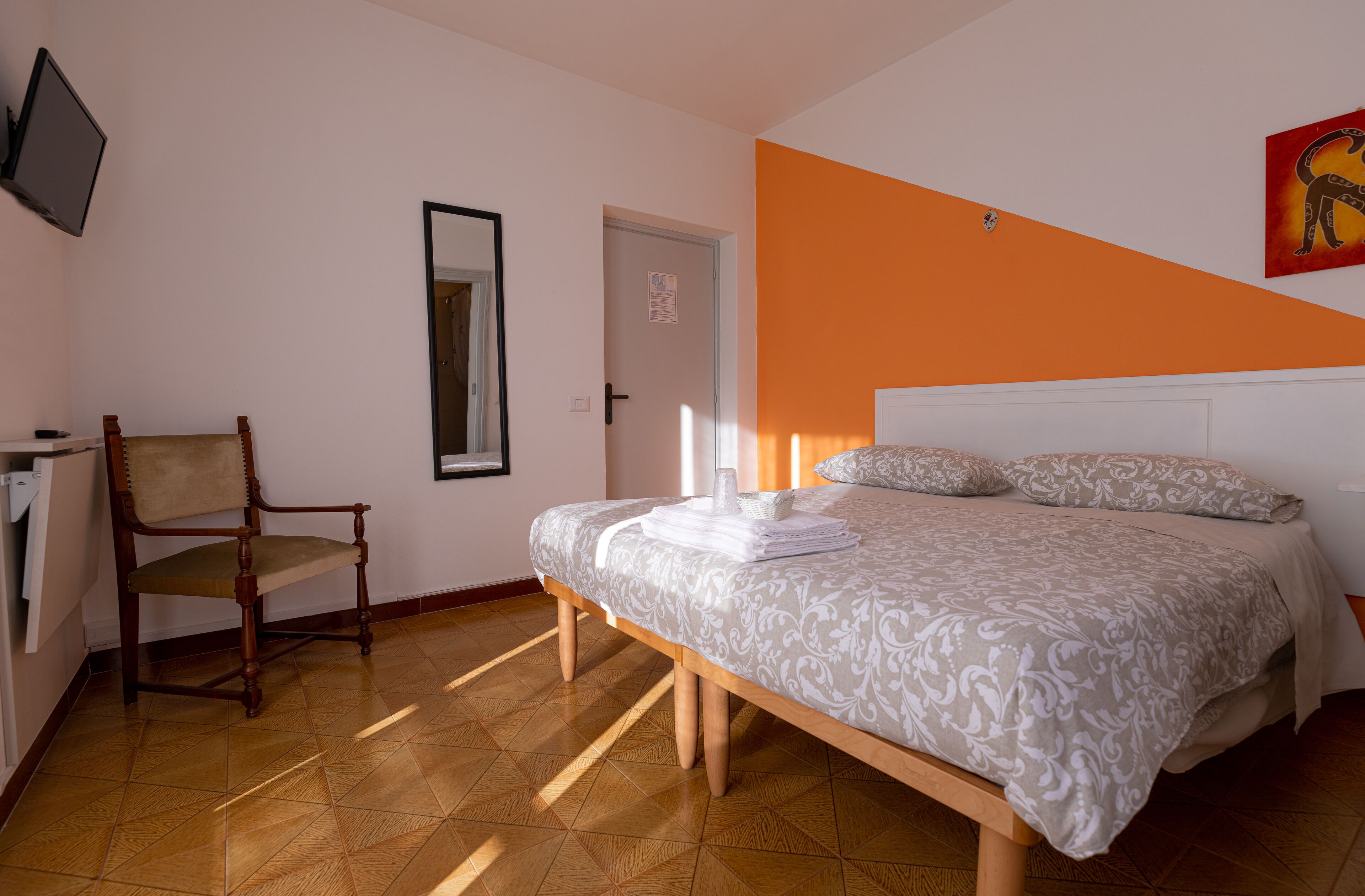 A bedroom with a bed, a chair, a television, and a door.