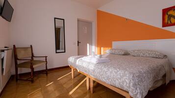 A bedroom with a bed, a chair, a television, and a door.