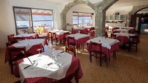 En restaurang med röd- och vitrutiga bordsdukar, valv av sten och trägolv.