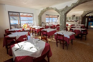 Un restaurante con manteles a cuadros rojos y blancos, arcos de piedra y suelo de madera.