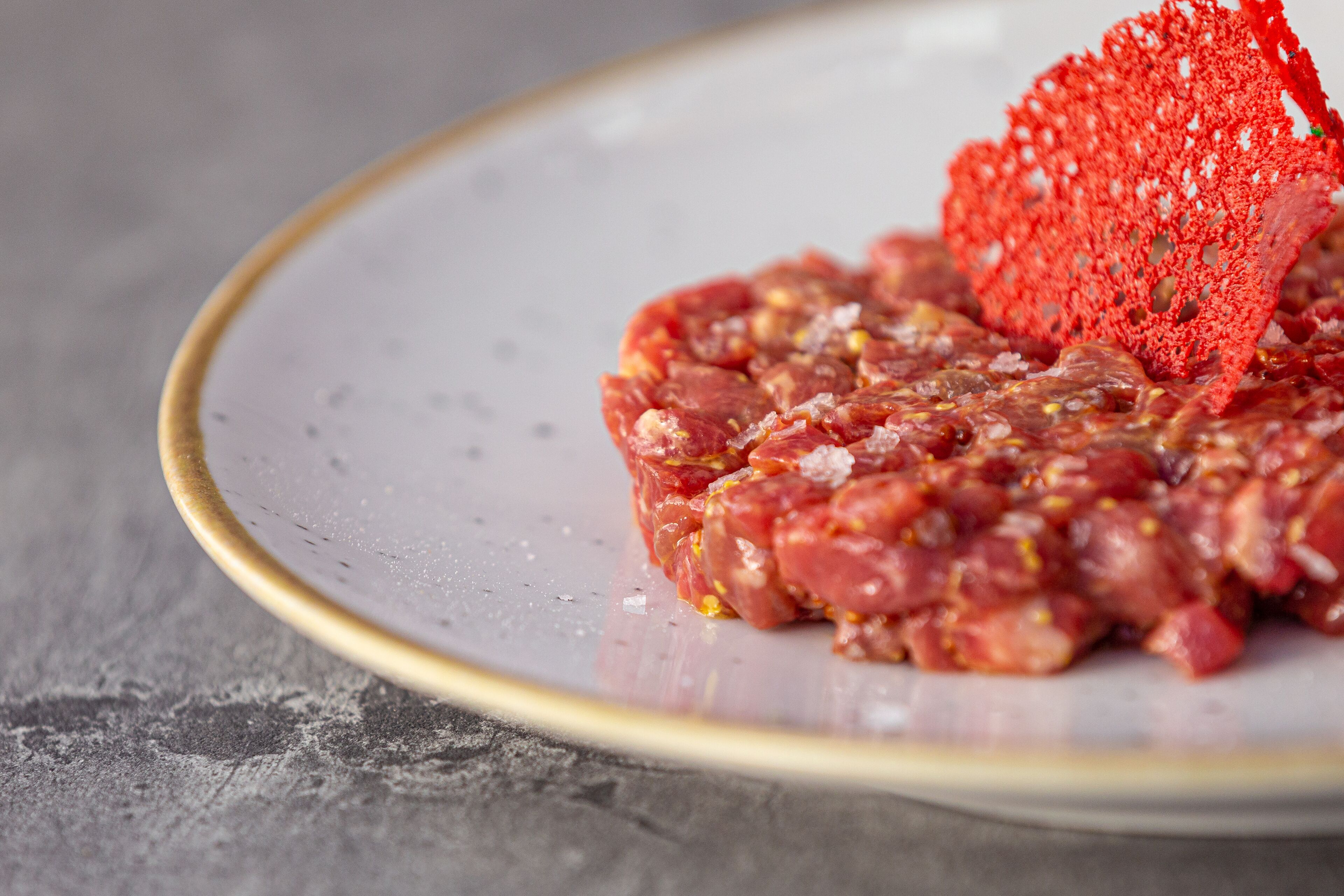 Un plato con carne cruda y un adorno rojo.