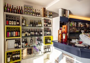 Una tienda de vinos y licores bien organizada, con múltiples estantes llenos de botellas y una gran variedad de productos.