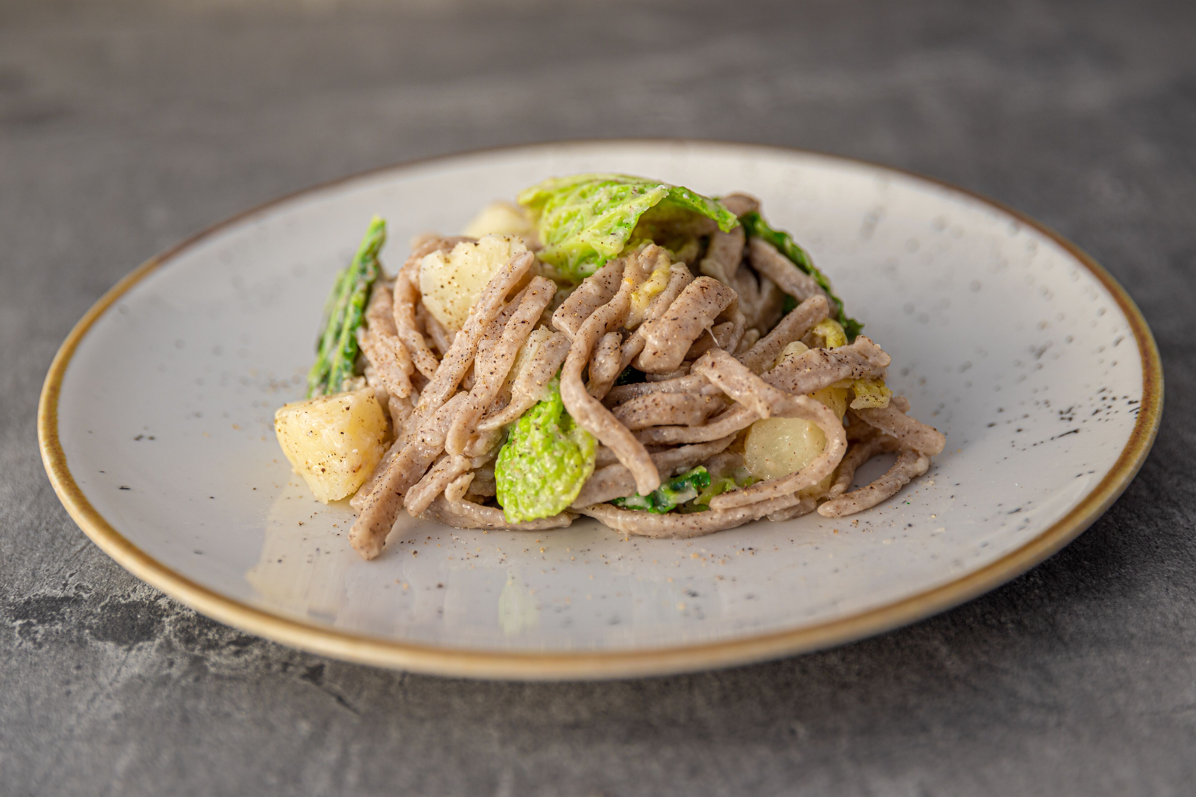 Un plato de pasta con verduras y carne.