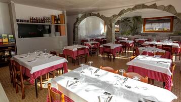 Un restaurante con mesas dispuestas para comer, una bodega de vinos y un mural en la pared.