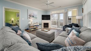 A living room with a fireplace, a television, and a large window with a view of the outdoors.