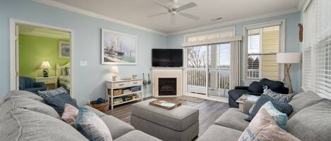 A living room with a fireplace, a television, and a large window with a view of the outdoors.