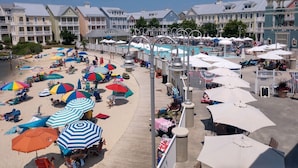 A beachside resort with a pool, beach umbrellas, and lounge chairs.
