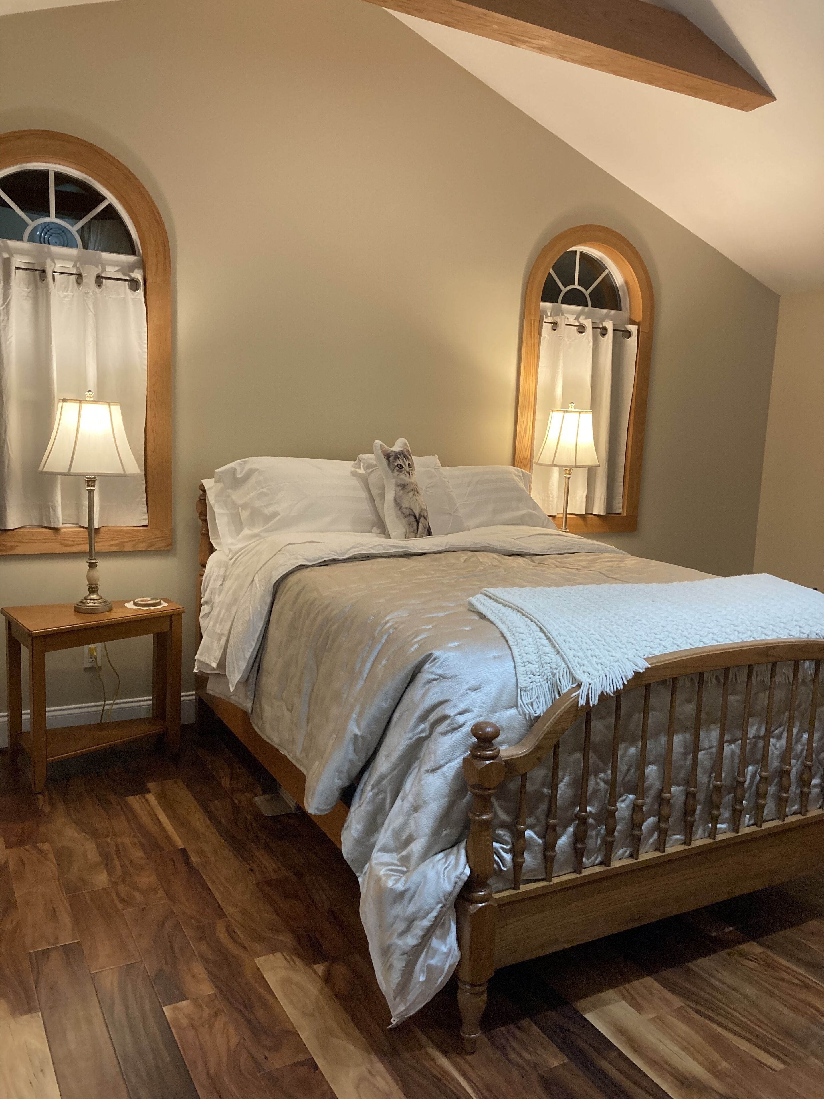Une chambre à coucher avec un lit en bois, deux lampes de chevet et une fenêtre avec un rideau.