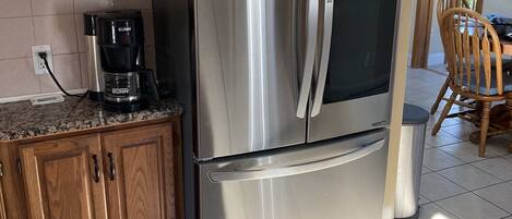 A kitchen with wooden cabinets, a stainless steel refrigerator, and a coffee maker.