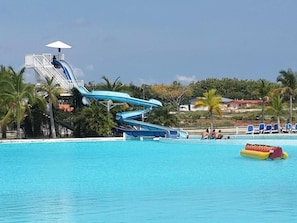 A water park with two water slides, a pool, and a lifeguard tower.