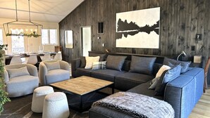 Una sala de estar moderna con un sofá modular, sillones, otomanas y una mesa de centro de madera.
