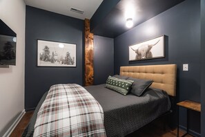 A bedroom with a bed, a headboard, a nightstand, and a wall-mounted TV.