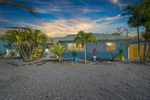 Una propiedad residencial con entrada de grava, varias plantas en macetas y una casa de color azul claro.