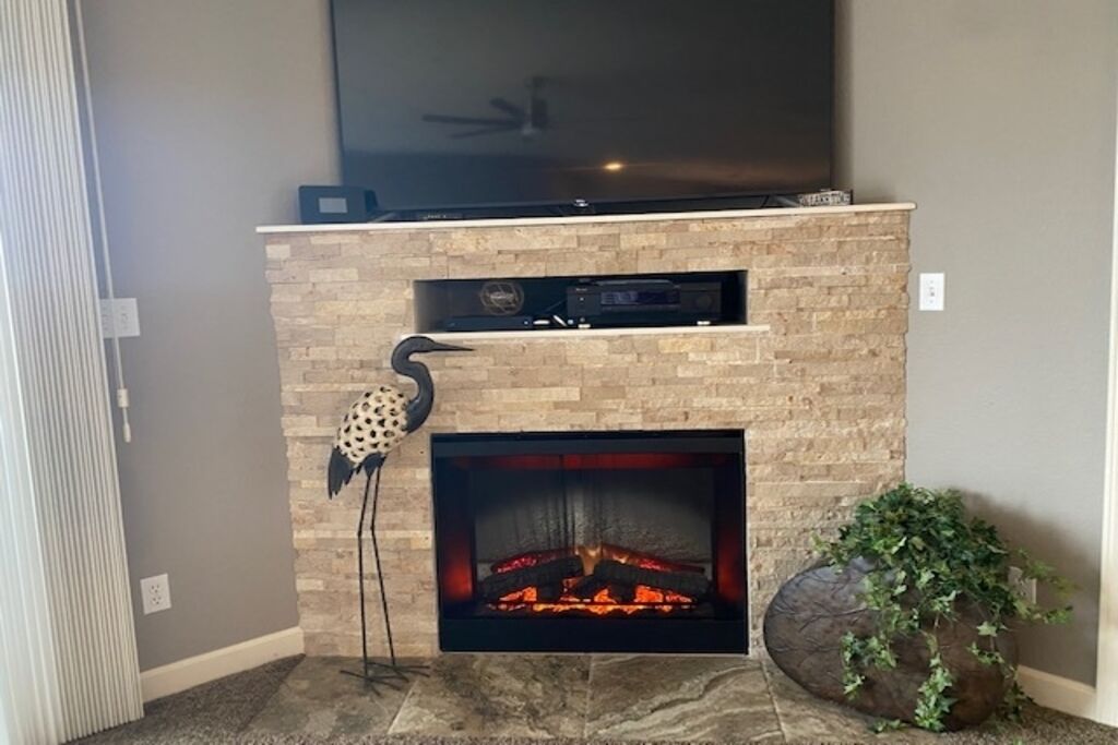 A fireplace with a stone facade, a flat-screen TV mounted above, and a decorative bird sculpture.
