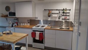 Et kompakt køkken med komfur, ovn, vask og mikroovn.
