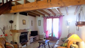 Ein gemütliches Wohnzimmer mit Kamin, Ledersofas, Fernseher und einem gemusterten Teppich.