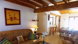 Ein geräumiges Wohnzimmer mit einer braunen Ledersofa, einem Couchtisch und einem Essbereich mit Holztisch und -stühlen.