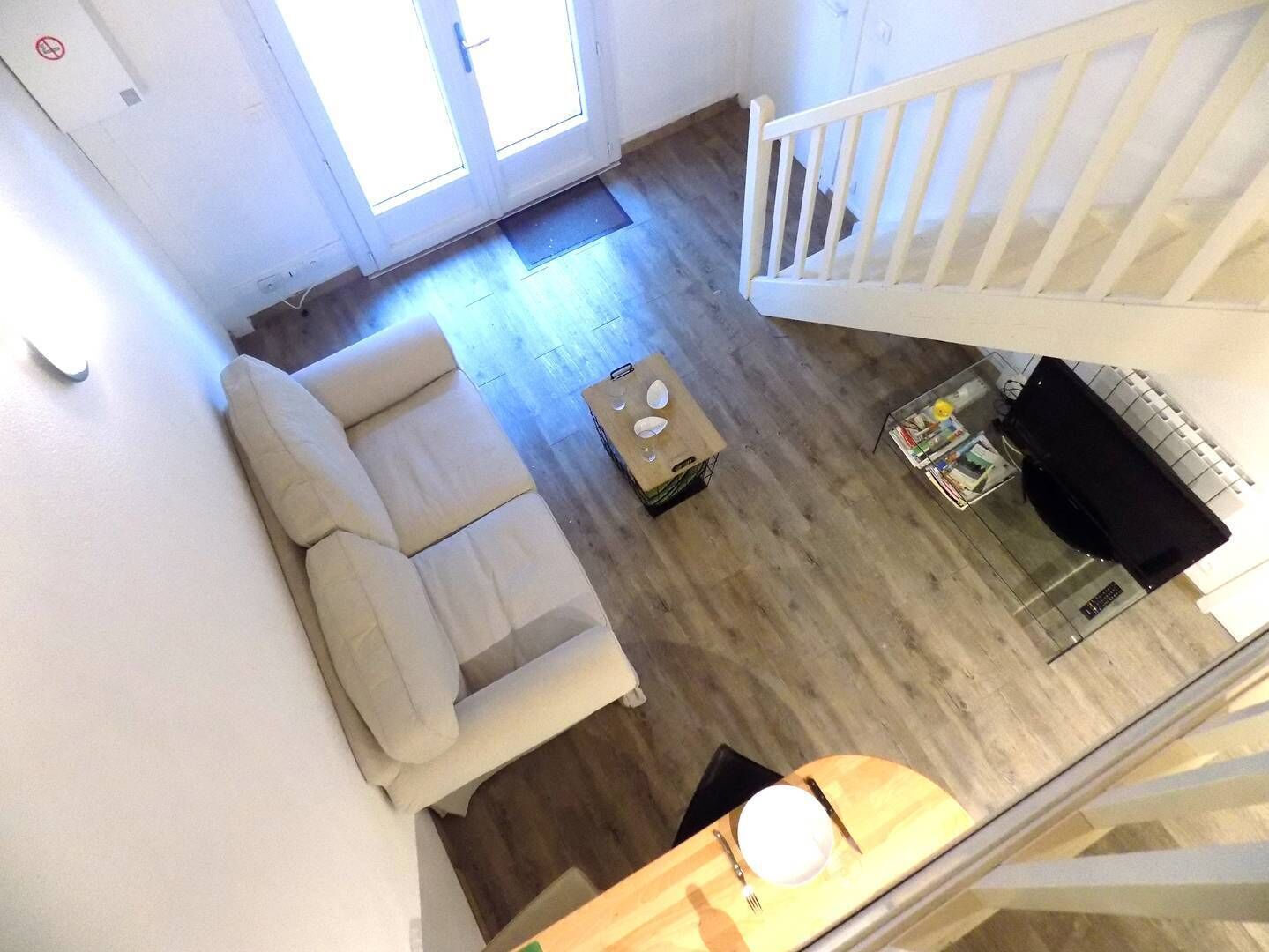A spacious living area with a sofa, a coffee table, and a dining table set up.