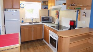 Una cocina compacta con refrigerador, pileta, estufa y microondas.
