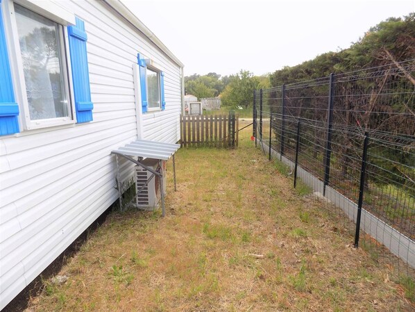 A mobile home with a small porch and a fenced yard.