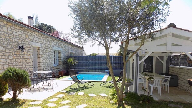 Uma casa de pedra com piscina, área de estar externa e pérgola.