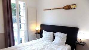 Quarto de hotel com uma cama, duas luminárias laterais, uma janela com cortinas e um objeto decorativo fixado na parede.