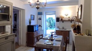 A dining area with a chandelier, a table set for two, and a view of the outdoors through a door. - Les Mathes La Palmyre - CHARMING CHARENTAISE HOUSE - PEACEFUL - COUNTRYSIDE (LES MATHES)
