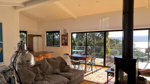 A modern living room with a sofa, a dining table, and a large window overlooking a scenic view.