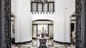 A lobby with a checkered floor, a central table with a globe, and ornate black metal gates.