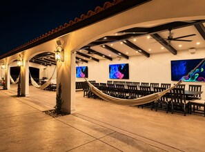 Un espacio al aire libre con patio, una hamaca, sillas y obras de arte en las paredes.
