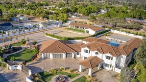 A large, single-story house with a spacious front yard, a swimming pool, and a well-maintained lawn.