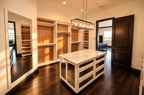 A modern kitchen with a marble countertop, built-in wooden shelving, and a pendant light.