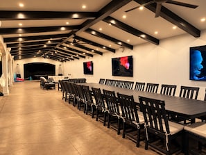 Uma sala de conferência com uma longa mesa, cadeiras, luminárias no teto e obras de arte nas paredes.