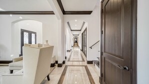 A hallway with a marble floor, a sofa, and a large wooden door.