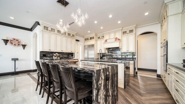 A spacious kitchen with a large island, dark wood chairs, and white cabinetry.