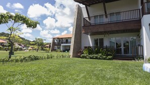 Une maison à deux étages avec un balcon, une pelouse bien entretenue et un ciel dégagé.