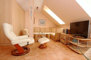 A cozy living room with a sofa, a TV, and a chair. - Comfortable vacation apartment in Zingst in the first row of the beach - Residenz am Strand (Zingst)