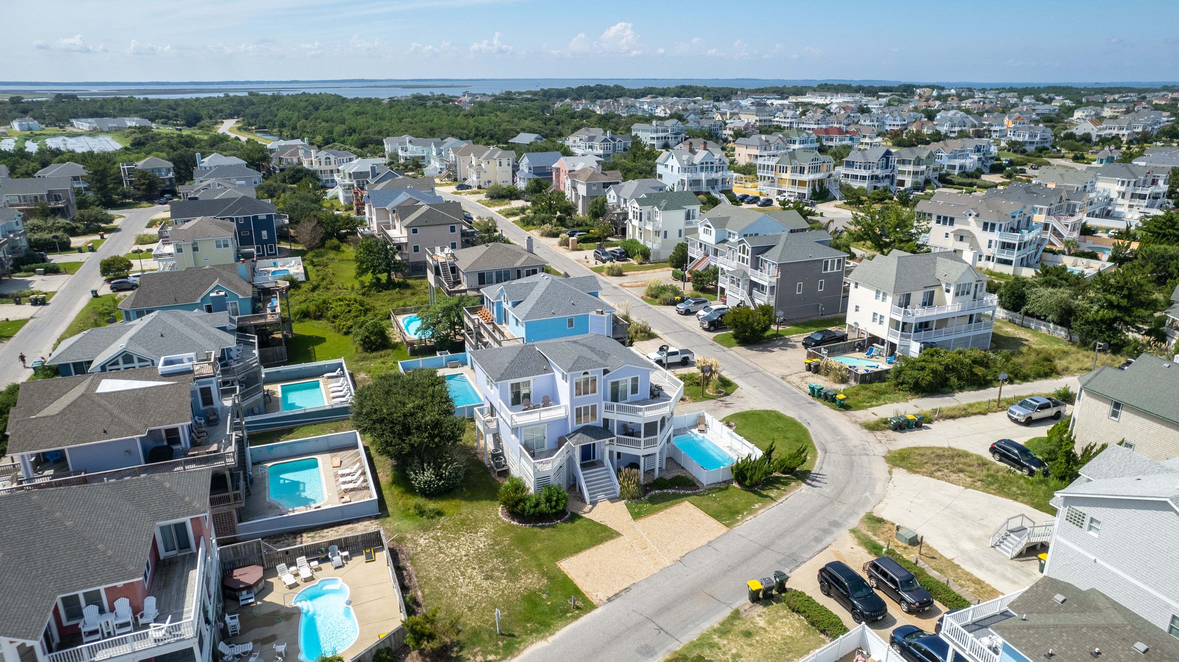 Un quartier résidentiel avec des maisons, une route et, au loin, une grande étendue d’eau.