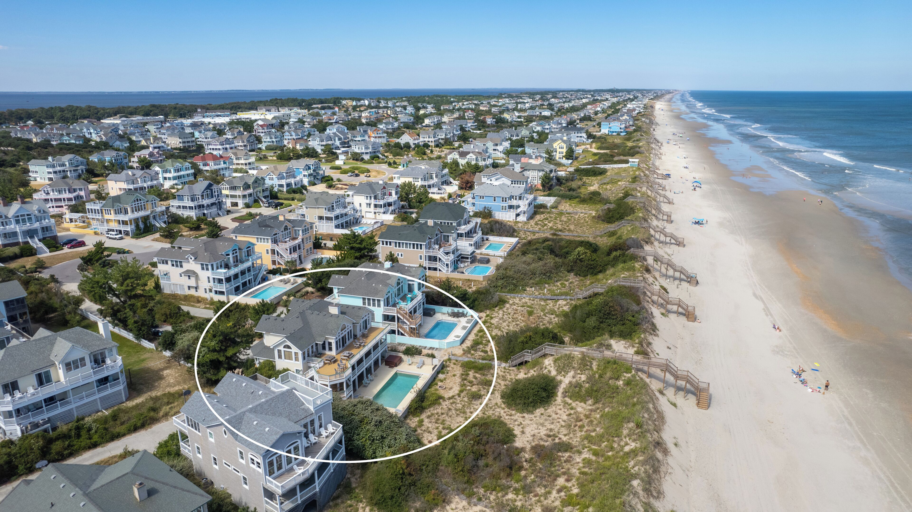 Un quartier résidentiel situé sur la côte, avec des maisons, une plage et une piscine.