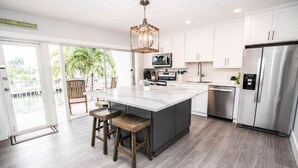 Una cocina moderna con una isla grande, electrodomésticos de acero inoxidable y vistas a un balcón.