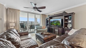 A spacious living room with leather sofas, a television, and a ceiling fan. - Destin West Osprey 604  ~ 3BR w/ Bay & Lazy River Views! (Fort Walton Beach)